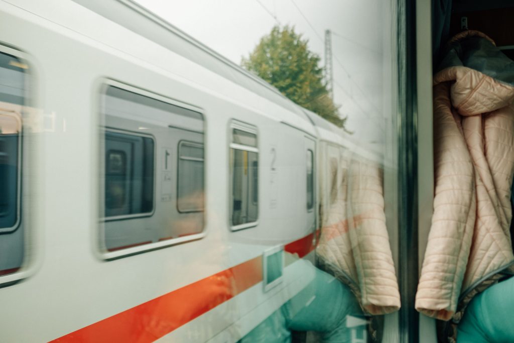 Blick durch das Fenster eines Zugabteils auf einen vorbeifahrenden Zug.