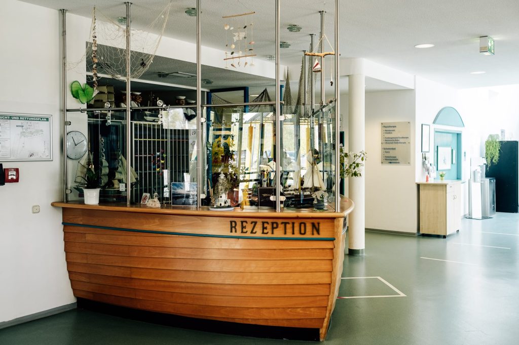 Die hölzerne Rezeption der Ostseeklinik Zingst in Form eines Schiffsbugs, maritim geschmückt mit Fischenetzen.